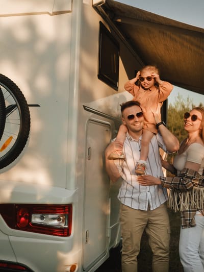 a-young-family-with-glasses-is-standing-next-to-the RV
